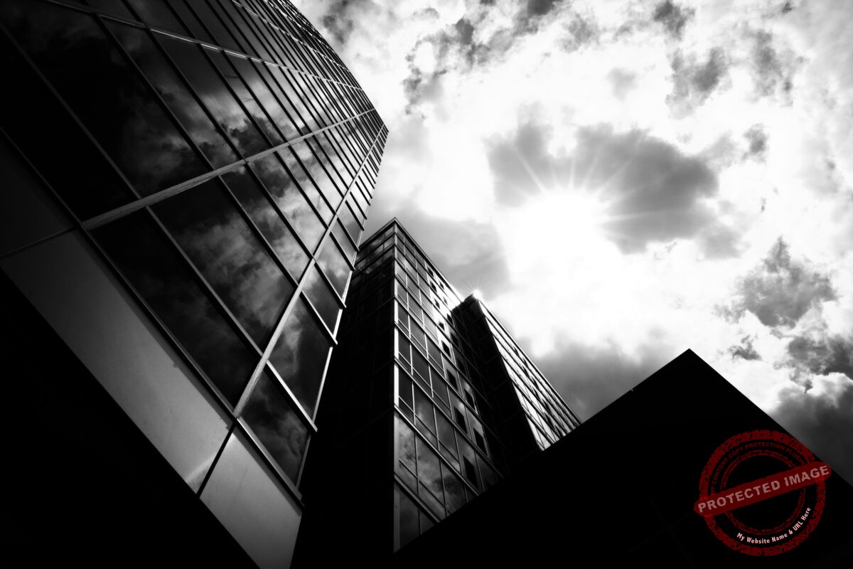 Low angle grayscale shot of business buildings with a cloudy sky in the background